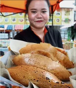  ??  ?? Tasty treats: A stall worker showing off freshly made ‘apom balik’ at the Apom Balik Triple Q stall along Jalan Relau, Penang.