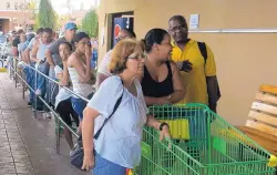  ?? BEN FOX/ASSOCIATED PRESS ?? People wait in line outside a grocery store in San Juan on Monday to buy food that wouldn’t spoil and that they could prepare without electricit­y.