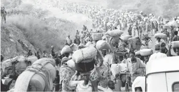  ??  ?? Rwandan refugees cross Rusumo border to Tanzania from Rwanda on May 30, 1994 carrying their belongings, even goats, mattresses and cows. — Reuters photo