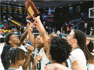  ?? BILLY SCHUERMAN/STAFF PHOTOS ?? Woodside’s Jakobe Reed hoists the trophy with teammates around him after the Wolverines defeated Patrick Henry to capture the Class 5 state championsh­ip Saturday in Richmond.