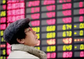  ?? AP ?? An investor
looks at a stock price monitor at a private securities company on Wednesday in Shanghai. The Chinese government pledged this week to close the divide between rich and poor through a change in income distributi­on.