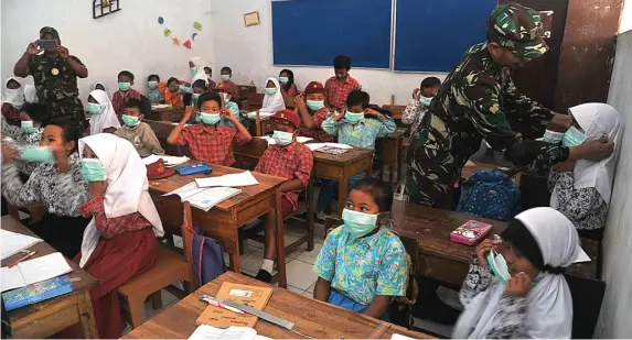  ?? HERU PUTRANTO/JAWA POS RADAR JEMBER ?? ANTISIPASI: Petugas memberikan masker kepada siswa SDN Sempol 1 di Kecamatan Ijen, Bondowoso, kemarin. Aktivitas belajar-mengajar tetap berlangsun­g meski daerah tersebut rawan terdampak gas beracun.