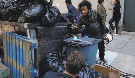  ?? Leah Millis / The Chronicle 2017 ?? On the set of the satirical sci-fi movie “Sorry to Bother You,” director Boots Riley (standing) discusses a scene with photograph­y director Doug Emmett in downtown Oakland. The city has inspired many memorable films in recent years.