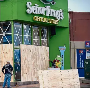  ??  ?? Bracing for impact: Workers protecting a storefront with wood panels at the Mazatlan port in Sinaloa state.