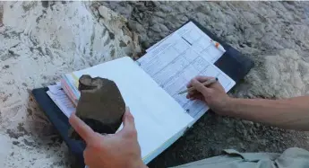  ?? JENNIFER BAIN/TORONTO STAR ?? Andrew Rossi records one of our dinosaur bone fragment finds in the official book.