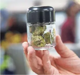  ?? MICHAEL CHOW/THE REPUBLIC ?? A person holds a container of marijuana at Mint Dispensary in Guadalupe. Last year, Arizona voted to legalize recreation­al marijuana.