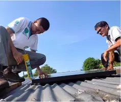  ??  ?? Wan (left) helps install the solar panel on the roof of Jean’s house.