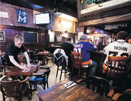  ?? ALLEN McINNIS ?? Adam Ramsey prepares tables as a few Islanders fans sit at the bar of McLean’s Pub hours before the Canadiens game on Wednesday.