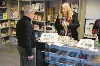  ?? JESSICA HILL/AP ?? Melissa Bird shows off newspaper carrier bags to Andy Thibault, editor and publisher of the Winsted Citizen on Friday.