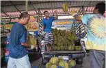  ?? ?? This photo shows durian vendors unloading durians from a truck to sell at Wat Si Muang temple.