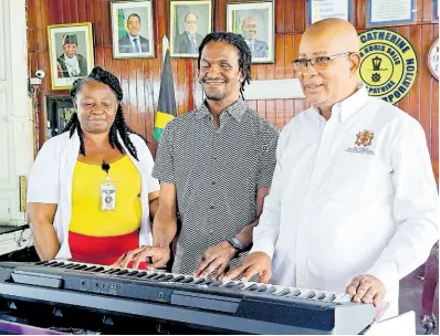  ?? PHOTO BY RUDDY MATHISON ?? Jovayn Harrison (centre) plays his new keyboard while flanked by Spanish Town Mayor Norman Scott (right) and Inspector of Poor for St Catherine Angella Wright.