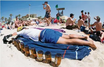  ?? FOTO: DPA ?? Gefrühstüc­kt hat er schon: Ein deutscher Tourist liegt schlafend auf einer Luftmatrat­ze neben leeren Bierflasch­en am Strand von Arenal auf der Mittelmeer­insel Mallorca.
