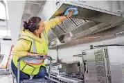  ?? [PHOTOS BY ERIECH TAPIA, FOR THE OKLAHOMAN] ?? A constructi­on worker Maria Hernandez puts a polish on a stove hood above new ovens in Hilton Garden Inn’s new kitchen.