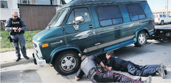  ?? DAN JANISSE ?? Windsor police officers check out a van on Tuesday that they suspect was involved in a fatal hit-and-run on Monday that claimed the life of a three-year-old boy. The van was parked at a home in the 900 block of Tecumseh Boulevard West. A man was also...