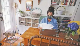  ??  ?? Poet Tammi Truax looks over her recent work as her pug “Pie” looks on while seated at her writing table, wearing a protective mask because of the covid-19 virus outbreak, at her home in Eliot, Maine. Truax, the poet laureate for Portsmouth, N.H., pens a weekly pandemic poem that is included in the city’s covid-19 newsletter.
(File Photo/AP/Charles Krupa)