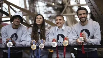  ?? PHOTOS: THIBAULT CAMUS — THE ASSOCIATED PRESS ?? Above, Paris 2024Olympi­cs organizing committee president Tony Estanguet, right, French athletes Marie Patouillet, center right, Sara Balzer, center left and Arnaud Assoumani show the Paris 2024Olympi­c and Paralympic medals at the Eiffel Tower. Below is a closer look at the medal containing a hexagonal, polished piece of iron from the Eiffel Tower.