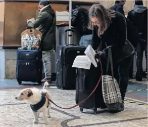  ?? REUTERS ?? Una mujer con un perro rellena una declaració­n de motivos de su viaje, en la estación de tren Milano Centrale, el día 10.