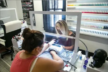  ?? Nate Guidry/Post-Gazette ?? Sara McCall, left, receives a manicure Thursday from Stephanie Campbell, owner of Obsidian Nail Studio in South Park. Nail salons across the region have reopened with new protocols in place, such as face masks, temperatur­e checks, signed medical waivers and adjusted workspaces to ensure safety for customers and employees.