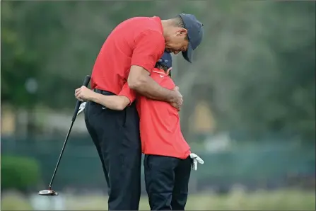  ?? The Associated Press ?? Tiger Woods, left, shares an embrace with son Charlie after the PNC Championsh­ip golf tournament on Dec. 20 in Orlando, Fla.