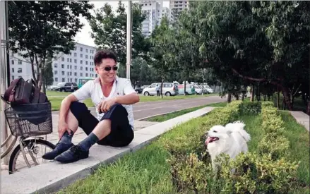  ?? ED JONES/AFP ?? A man sits beside a pet dog near Kim Il-sung Square in Pyongyang on July 19.