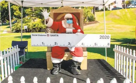  ?? JARROD VALLIERE U-T PHOTOS ?? “Social Distance” Santa waves to cars as they drive into Balboa Park for Taste of December Nights on Friday.