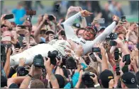  ?? FRANK AUGSTEIN / AP ?? Mercedes driver Lewis Hamilton is carried by fans after winning the British Formula One Grand Prix at Silverston­e, England, on Sunday.