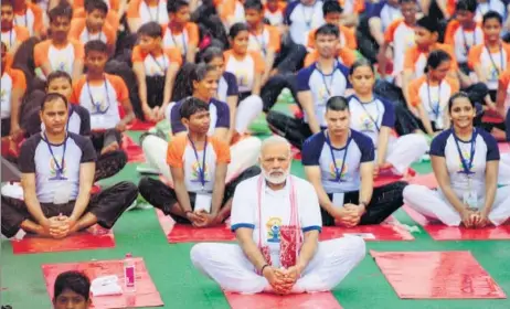  ?? DEEPAK GUPTA/HT PHOTO ?? Prime Minister Narendra Modi performs yoga with others at Ramabai Ambedkar Maidan on Wednesday. (Below) Enthusiast­s shield themselves from rain.