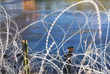  ?? Robert Gauthier Los Angeles Times By Faith E. Pinho ?? PEOPLE WADE in the Rio Grande along a razor-wire fence after crossing the U.S.-Mexico border in Eagle Pass, Texas, in September.