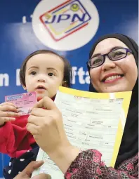  ?? AMIRUL SYAFIQ MOHD DIN/ THE SUN ?? Maizura Mat Radzi with her daughter Nurul Izzah Mahathir, who is showing off her 'MyKid' novelty card at the MyKad DPP Hub in Kuala Lumpur yesterday.