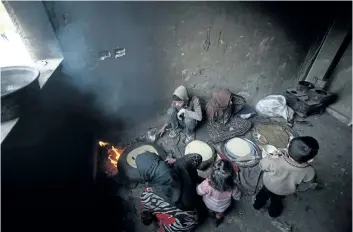  ?? ABDULMONAM EASSA/ GETTY IMAGES ?? Syrians cook bread inside a school turned into a shelter for people displaced by the war, in the rebel- controlled town of Hamouria, in the eastern Ghouta region on the outskirts of the capital Damascus.