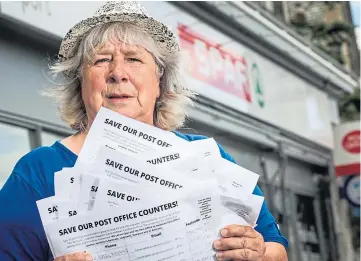  ?? ?? UNHAPPY: Campaigner Betty Martin, with some of the hundreds of petitions she has collected, outside Newport post office. Picture by Mhairi Edwards.