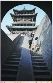  ?? ZHANG WEI / CHINA DAILY ?? Visitors negotiate the steps up to the city walls of Pingyao.