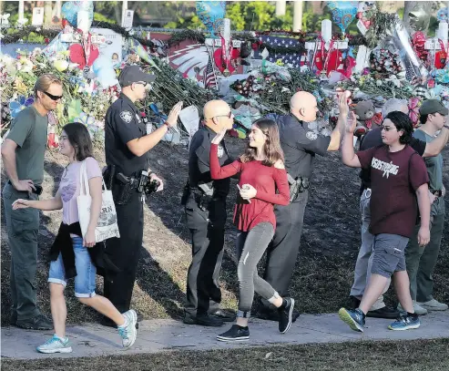  ?? MIKE STOCKER / SOUTH FLORIDA SUN- SENTINEL VIA AP ?? Students high-five police officers at Marjory Stoneman Douglas High School in Parkland, Fla., on Wednesday.