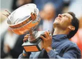  ?? Pavel Golovkin / Associated Press ?? Spain’s Rafael Nadal lifts the cup after defeating Austria’s Dominic Thiem for his 12th French Open title.