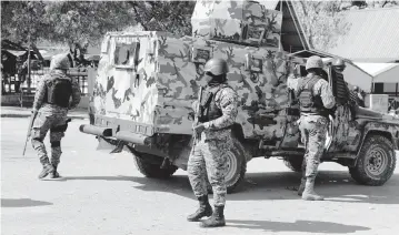  ?? ODELYN JOSEPH AP ?? Members of the General Security Unit of the National Palace set up a security perimeter around one of the three downtown stations after police fought off an attack by gangs the day before, in Port-au-Prince, Haiti, earlier this month.