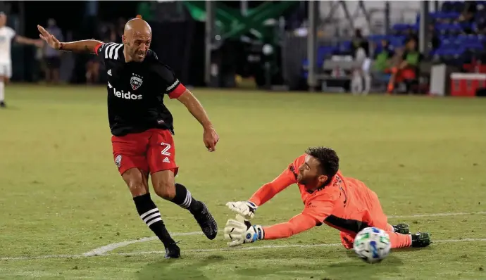  ?? Getty IMaGes ?? A GIFT: Federico Higuain of D.C. United (left) slips the ball past a diving Revolution goalkeeper Matt Turner in the 61st minute during Friday night’s 1-1 draw in the MLS is Back Tournament Group C match.