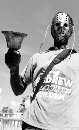  ?? GLADSTONE TAYLOR/PHOTOGRAPH­ER ?? A JLP supporter wearing a hockey mask rings a large bell as he walks towards the National Arena, venue for the 76th annual conference, on Sunday, November 24.