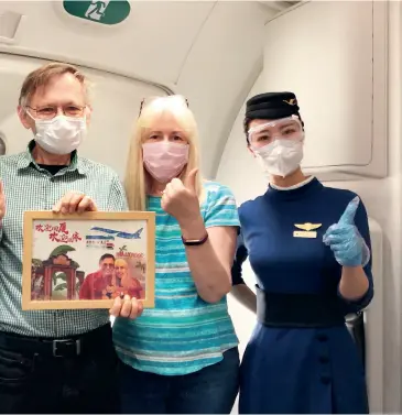  ?? Ran Yiran ?? William Brown and his wife pose for a group photo with stewardess­es of Xiamen Airlines.