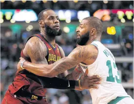  ??  ?? The Cavaliers’ LeBron James, left, is defended by the Celtics’ Marcus Morris.