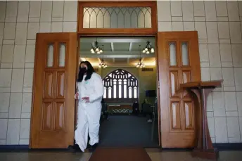  ?? Kevin Mohatt, Special to The Denver Post ?? A cemetery worker exits the chapel where family members attend the funeral service for Tin Aye.