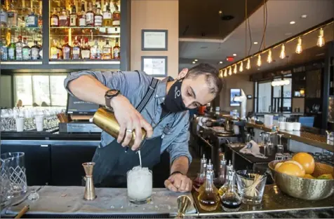  ?? Andrew Rush/Post-Gazette ?? Aaron Buettner, bartender at Spirits & Tales at the Oaklander Hotel, prepares an apricot bramble cocktail on Friday in Oakland.