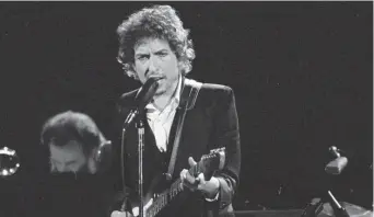  ?? JEFF ROBBINS/AP ?? Musician Bob Dylan performs with The Band at the Forum in Los Angeles on Feb. 15, 1974. Dylan, 79, was close friends with Tony Glover, who died last year. The two men broke into music on the same Minneapoli­s coffeehous­e scene. Glover’s widow, Cynthia Nadler, put the interview documents up for auction, with online bidding to start Nov. 12 and run through Nov. 19.