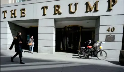  ?? MARY ALTAFFER / AP ?? Pedestrian­s and a food delivery man are seen outside the Trump building on Wall Street, in New York’s Financial District, on March 23. New York’s attorney general sued former president Donald Trump and his company on Wednesday, alleging business fraud involving some of their most prized assets, including properties in Manhattan, Chicago and Washington DC.