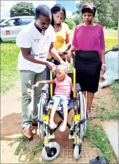  ?? (Courtesy pics) ?? The three-year-old boy with a disability sitting on his wheelchair donated by Cheshire Homes. From R is Cheshire Homes Director Khabo Dlamini, Sthembile Motsa, the mother of the child, and Rehabilita­tion Technician Artwell Ndebele (L).
