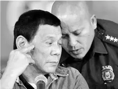  ??  ?? Duterte listens as Dela Rosa whispers to him, during a late night news conference at the presidenti­al palace in Manila. — Reuters photo