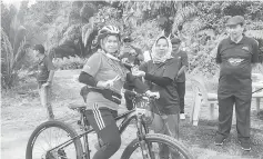  ??  ?? Assistant Minister of Women, Family and Childhood Developmen­t Rosey Yunus presents a rider with a medal.