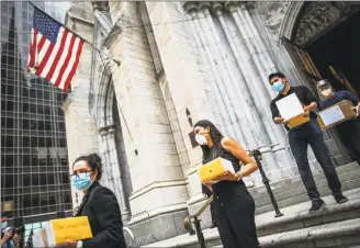  ?? Eduardo Munoz Alvarez / Associated Press ?? Mourners carry out the remains of loved ones following the blessing of the ashes of Mexicans who died from COVID- 19 at St. Patrick's Cathedral on Saturday in New York. The ashes were blessed before they were repatriate­d to Mexico.