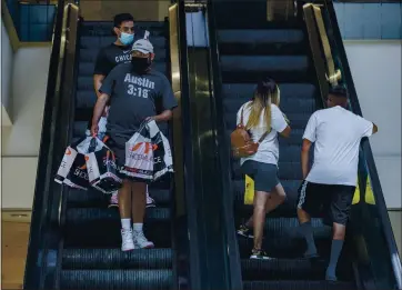  ?? TERRY PIERSON — SOUTHERN CALIFORNIA NEWS GROUP ?? Shopper Thomas Madril carries bags holding nine pairs of shoes he bought at a store in the Galleria at Tyler on Tuesday as the Riverside mall reopened after months of closure due to COVID-19.