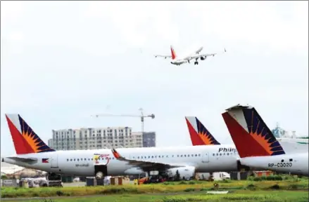  ?? TED ALJIBE/AFP ?? Philippine Airlines planes are parked while another takes off at Ninoy Aquino Internatio­nal Airport in Manila.