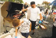  ?? Scott Strazzante / The Chronicle ?? Raymond Brown and son Austin, 11, grill hot dogs and burgers for evacuees Monday at a pop-up free barbecue in Redding.